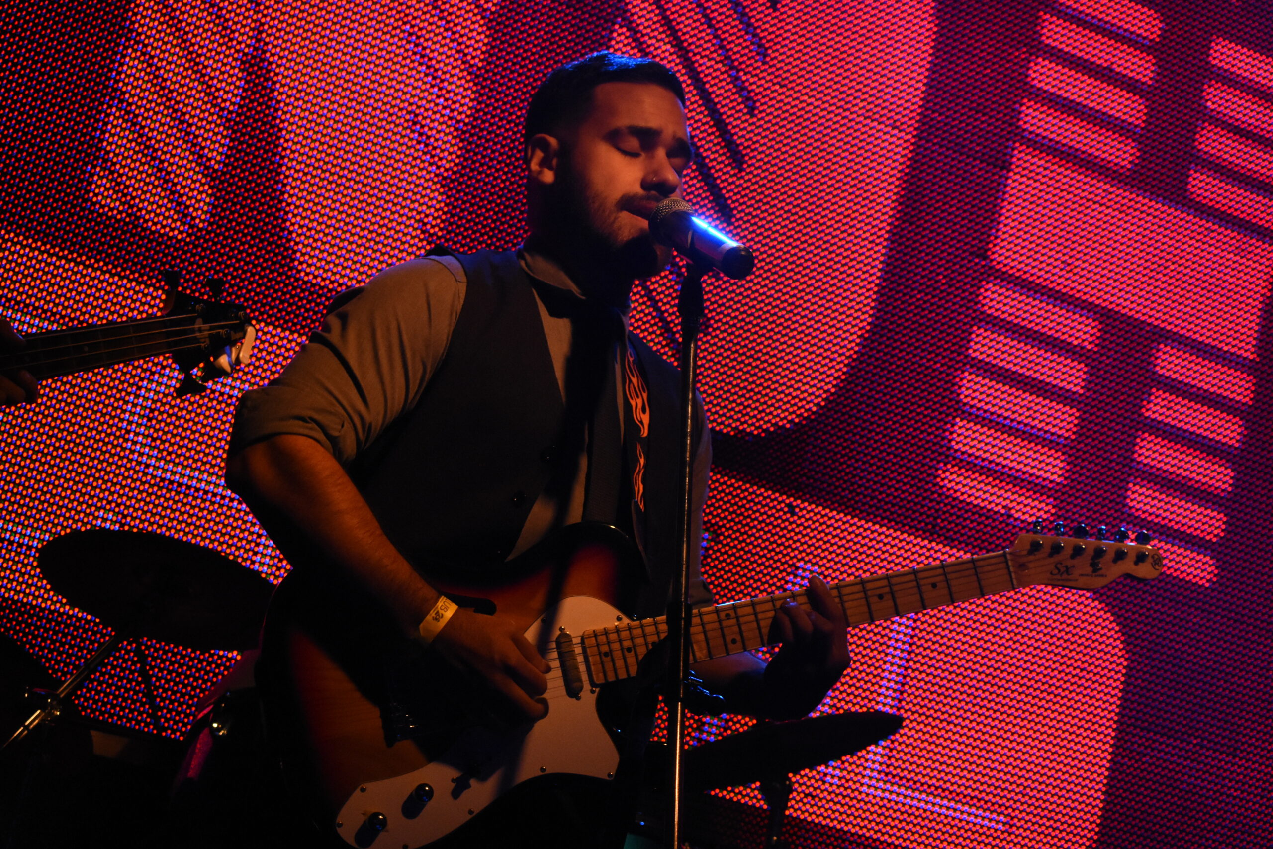 Foto de Emi, el cantante y guitarrista de Fue Un Gusto tocando en Niceto Club, sobre el escenario. De fondo se vé el logo de "ONOH"